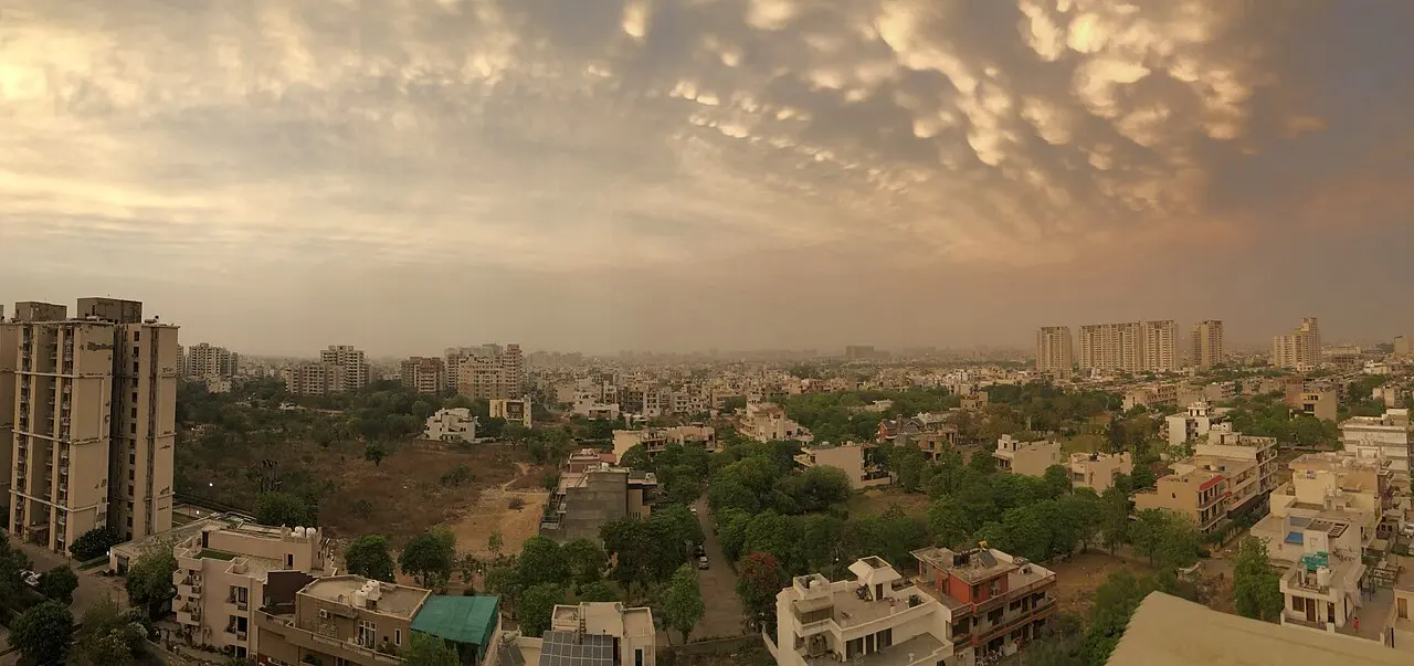 Panorama of Gurgaon at dusk beneath a dramatic sky