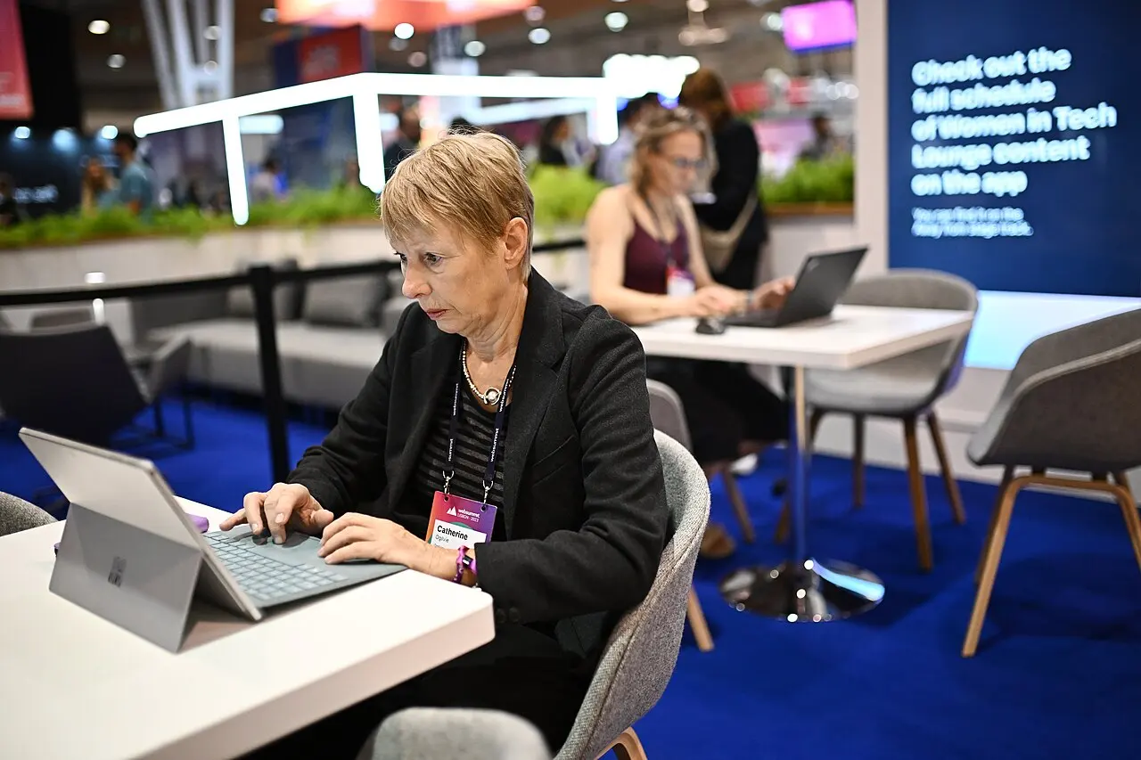 Woman using a laptop in a busy technology lounge