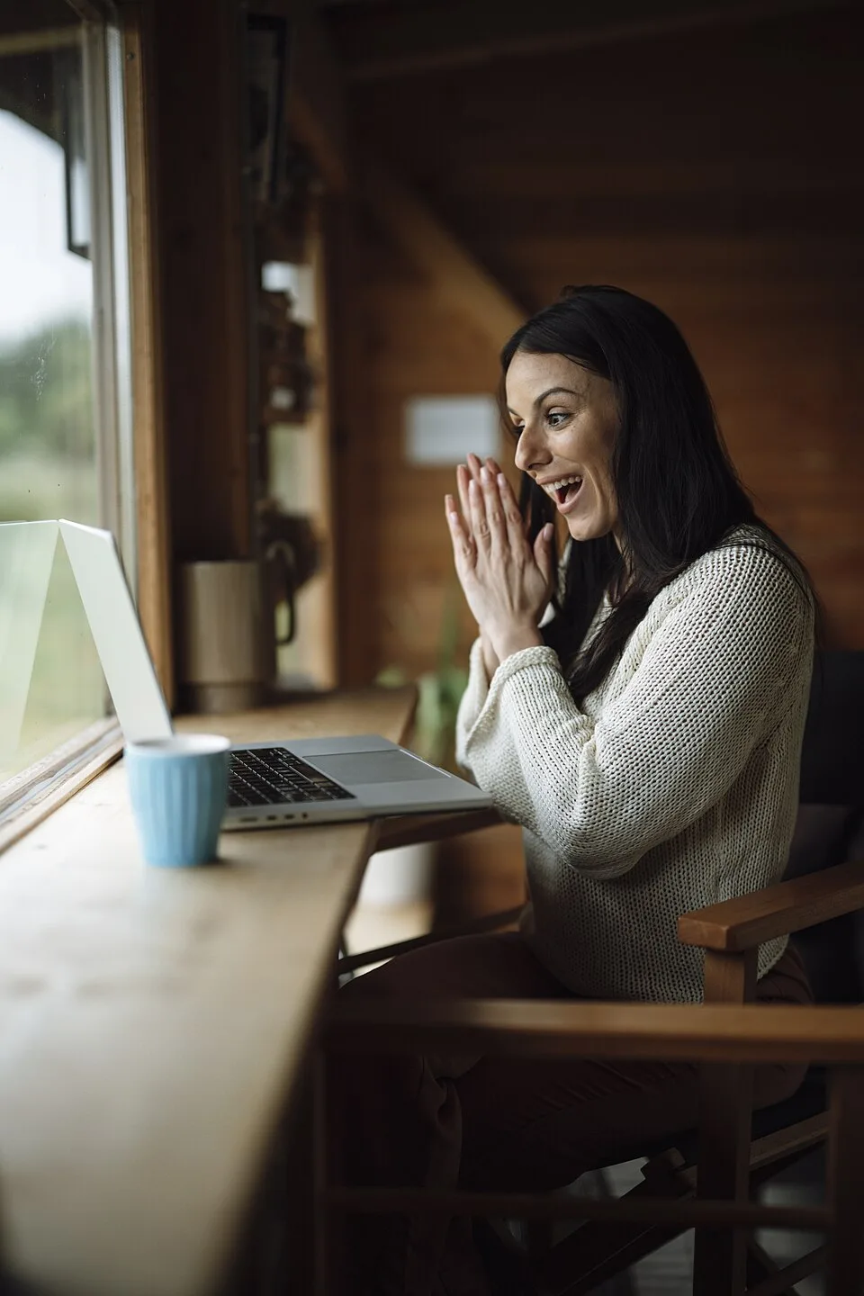Adult woman reacting to a video call on a laptop in a cabin